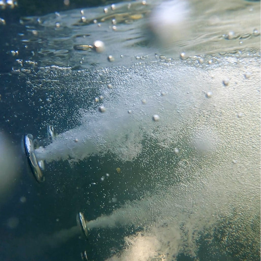 Vue sous-marine de deux jets d'eau métalliques libérant des jets de bulles dans un environnement d'eau claire