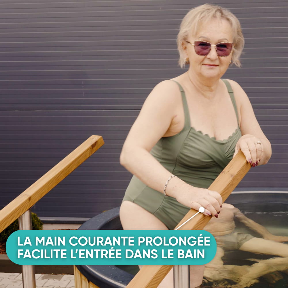 Femme se tenant à la main courante rallongée des marches Premium en entrant dans le bain nordique