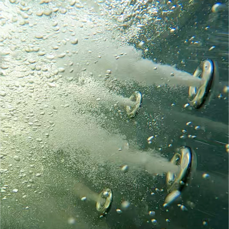 Gros plan sous-marin de quatre buses à jet libérant des jets de bulles dans l'eau