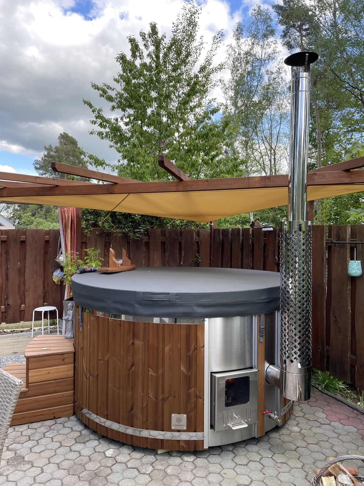 Gardenvity wood fired hot tub with stainless steel stove in a cozy garden corner.