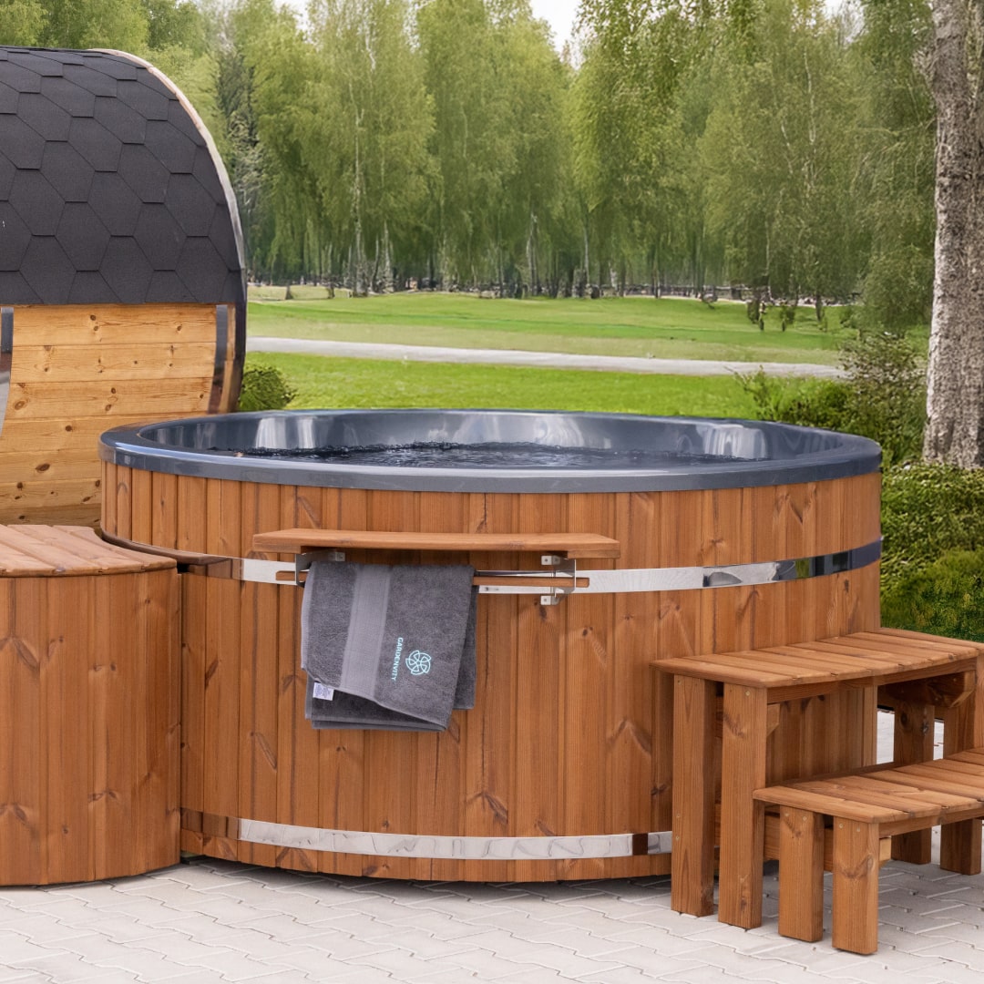 Vue extérieure du sauna bain nordique chauffé au bois, avec intérieur sombre, marches en bois, porte-serviettes et cabine de sauna hexagonale à proximité.