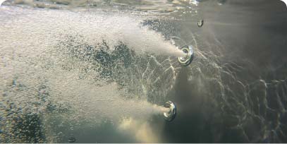 Jets d'hydromassage créant un mouvement d'eau à l'intérieur d'un bain nordique chauffé au bois