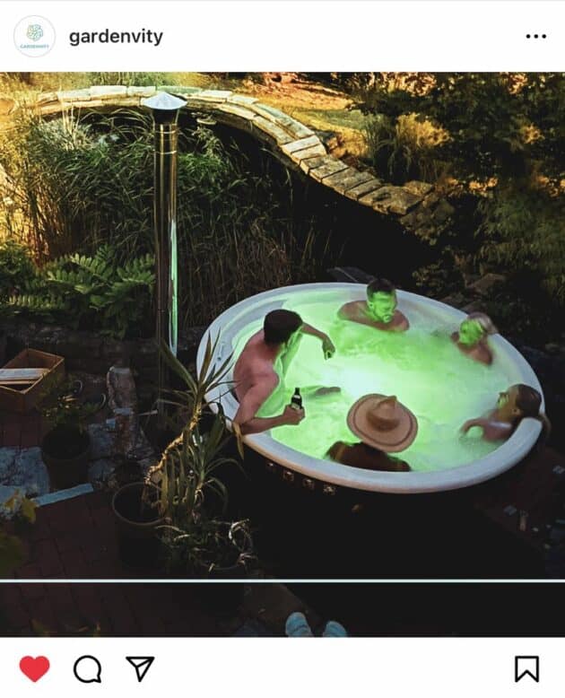 Un bain à remous de jardinvity avec un éclairage LED vert le soir, utilisé confortablement par 5 personnes